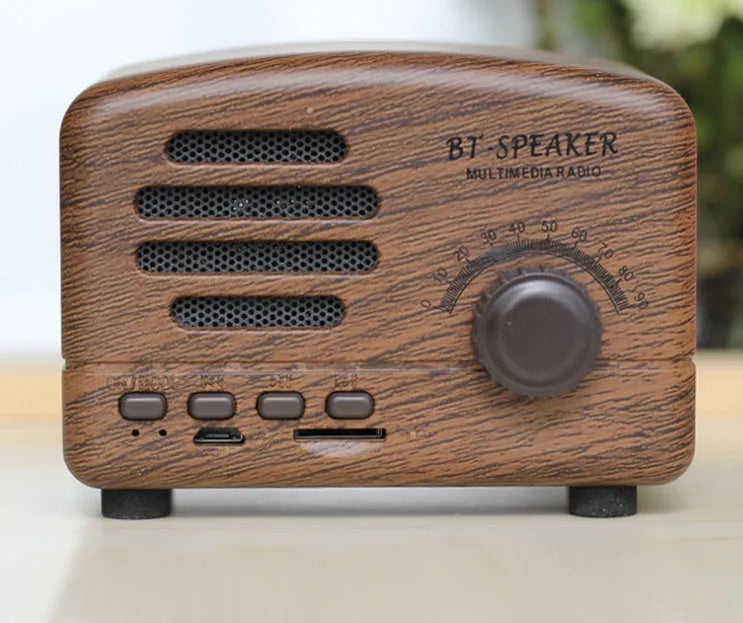 Compact Bluetooth speaker with wood grain finish, showing front grill and control buttons.