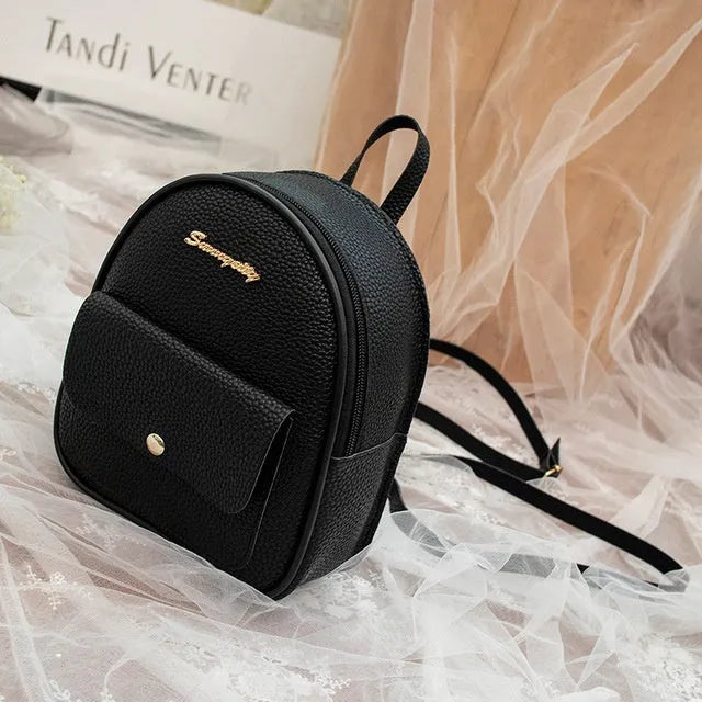 Small black PU women's backpack with zip, shown alongside a mobile phone for scale