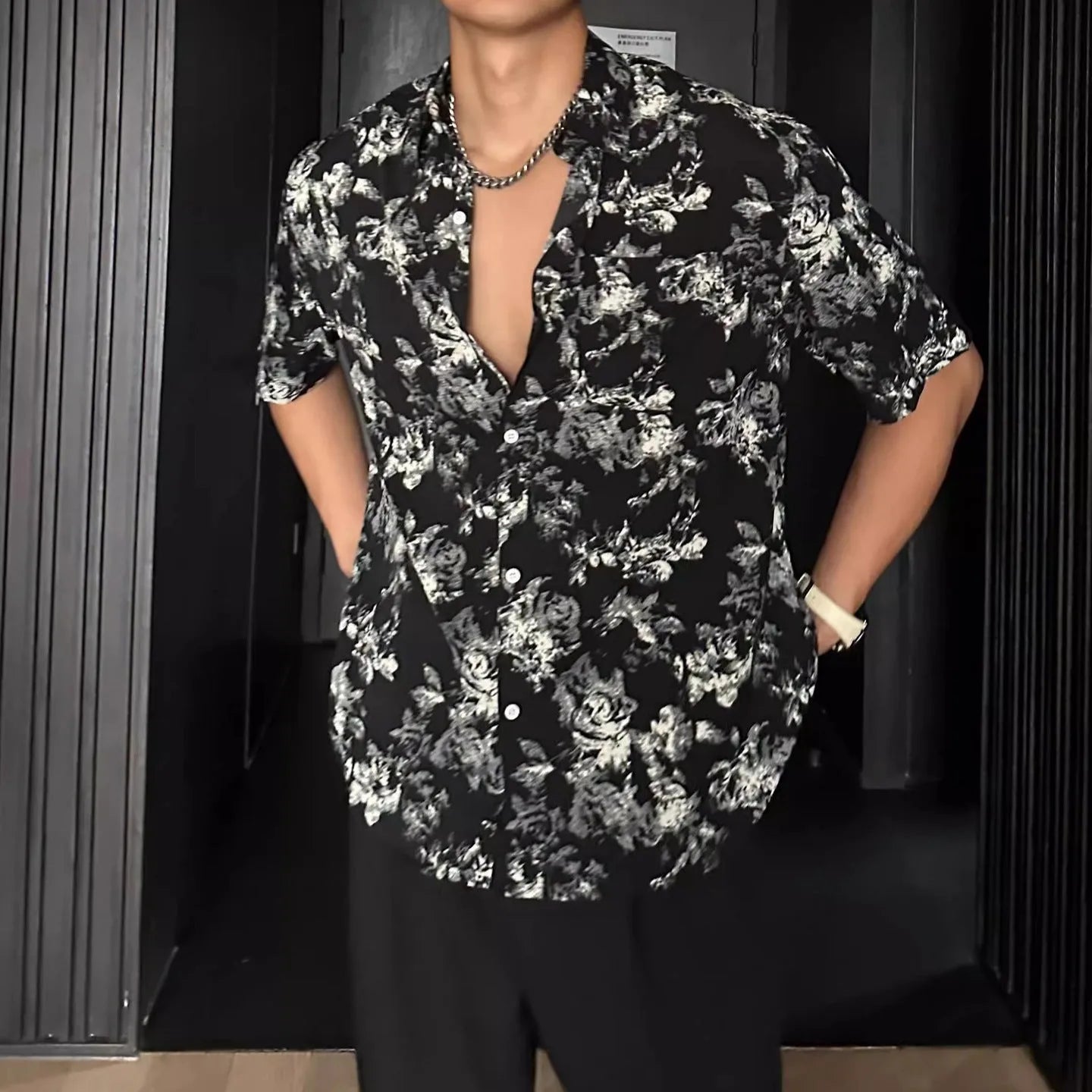 Man wearing a loose black short-sleeve shirt with a floral printed pattern.