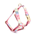 Pink dog harness with colourful heart-shaped stones and a gold-coloured buckle on a white background.