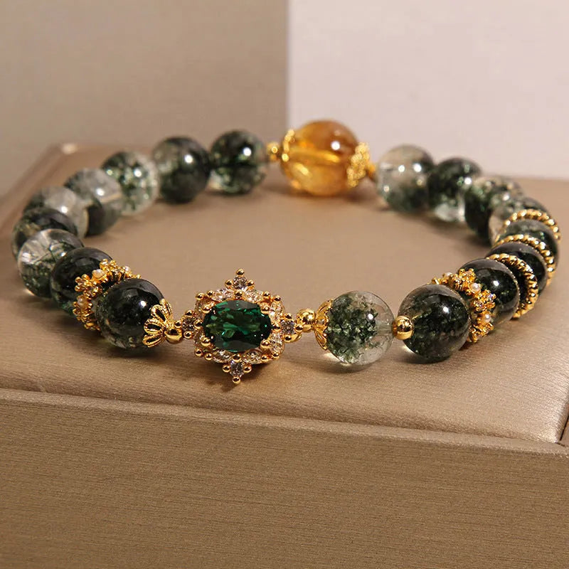Women's green phantom quartz crystal bracelet with gold rutile needles, ruby quartz bead, pearls, and rhinestone details.