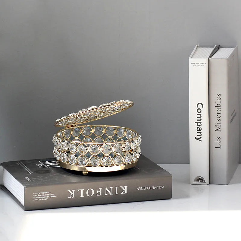 French gold metal jewelry box with a clear crystal glass lid and a lock, shown on a surface.