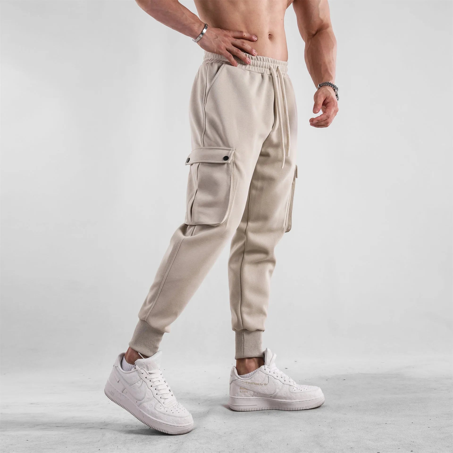 Men's loose grey cotton sports trousers with ankle ties and multiple pockets laid flat.