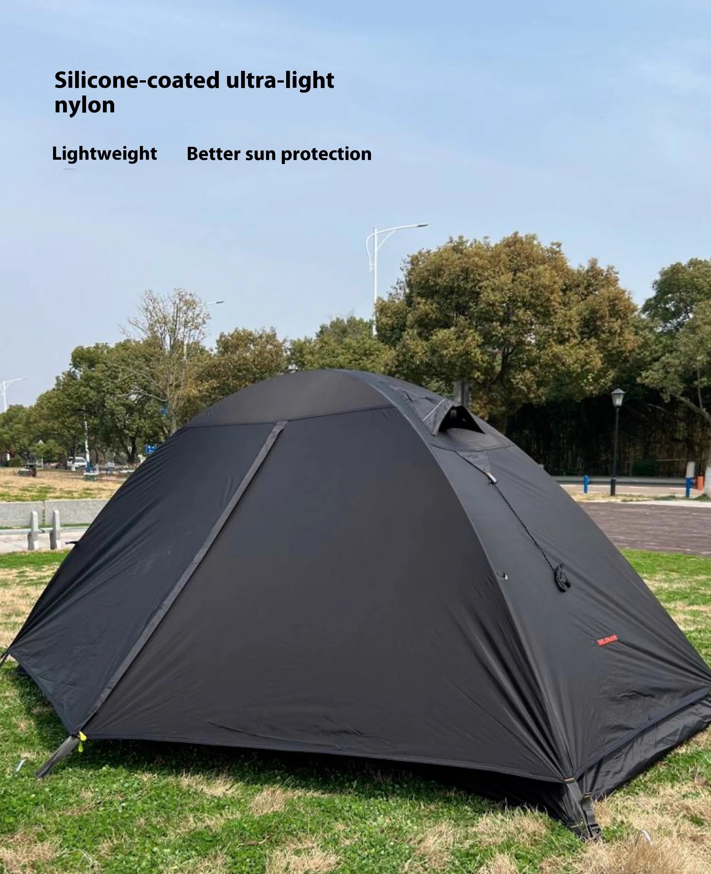 Red single person double-layer tent with aluminium poles set up outdoors.