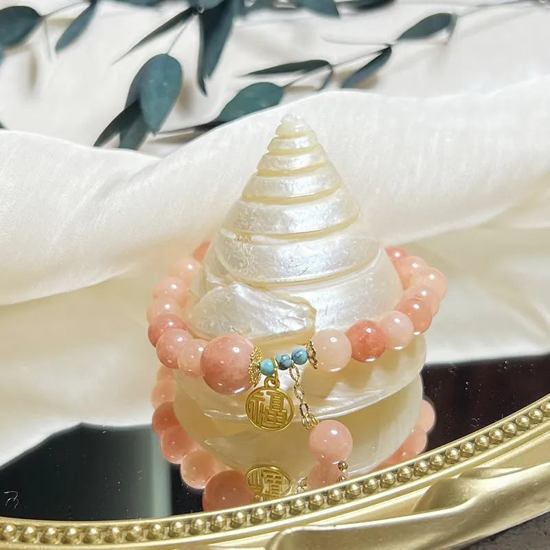 A simple pink natural stone and alloy bracelet with an adjustable clasp on a wrist.