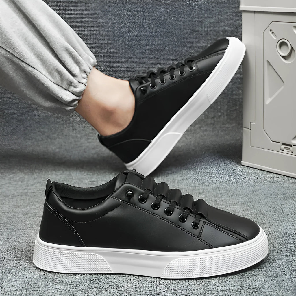 Men's black and white low top synthetic leather sports shoes with PVC sole on a plain background.