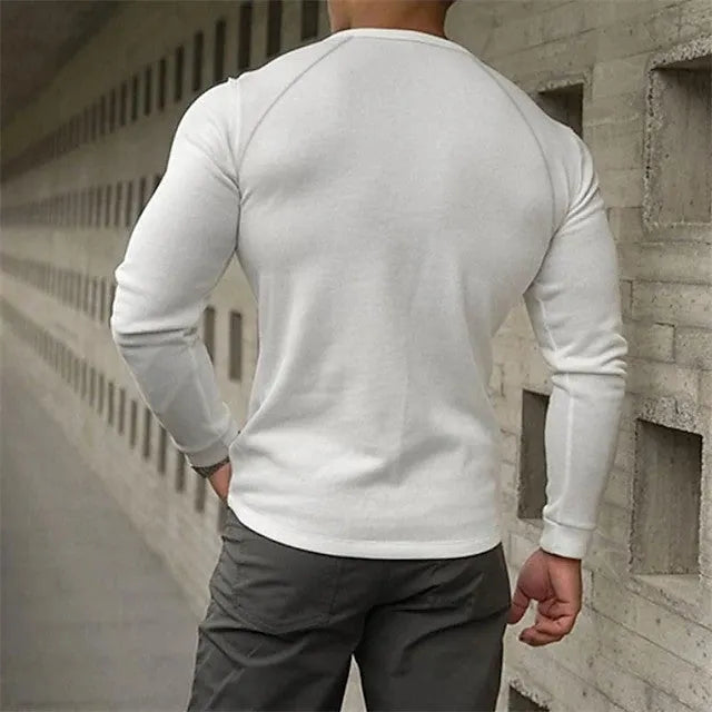 Man wearing a navy blue long-sleeved T-shirt with a Henry collar, made from cotton blend fabric.
