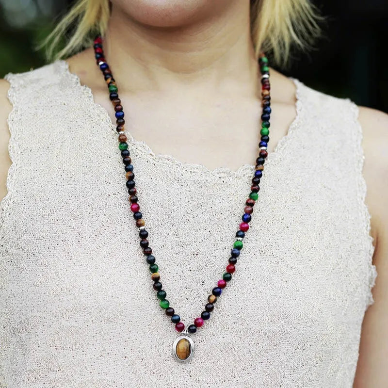 Close-up of a tiger-eye stone bead necklace with 108 gem-inlaid pendants showing heart, crown, and infinite symbols.