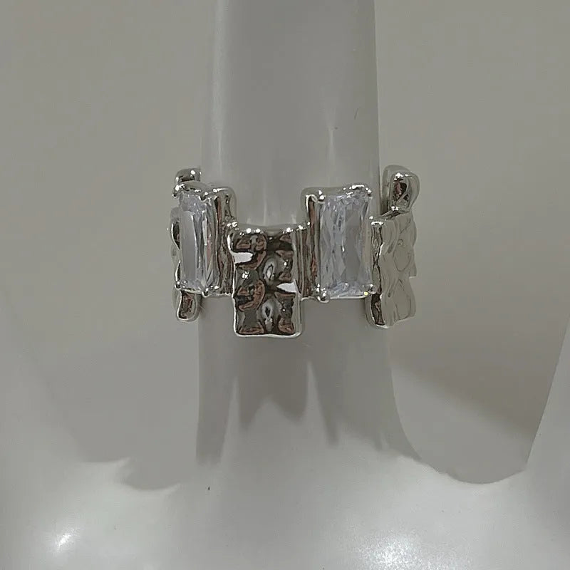 Silver geometric cross ring with open zircon stone setting.