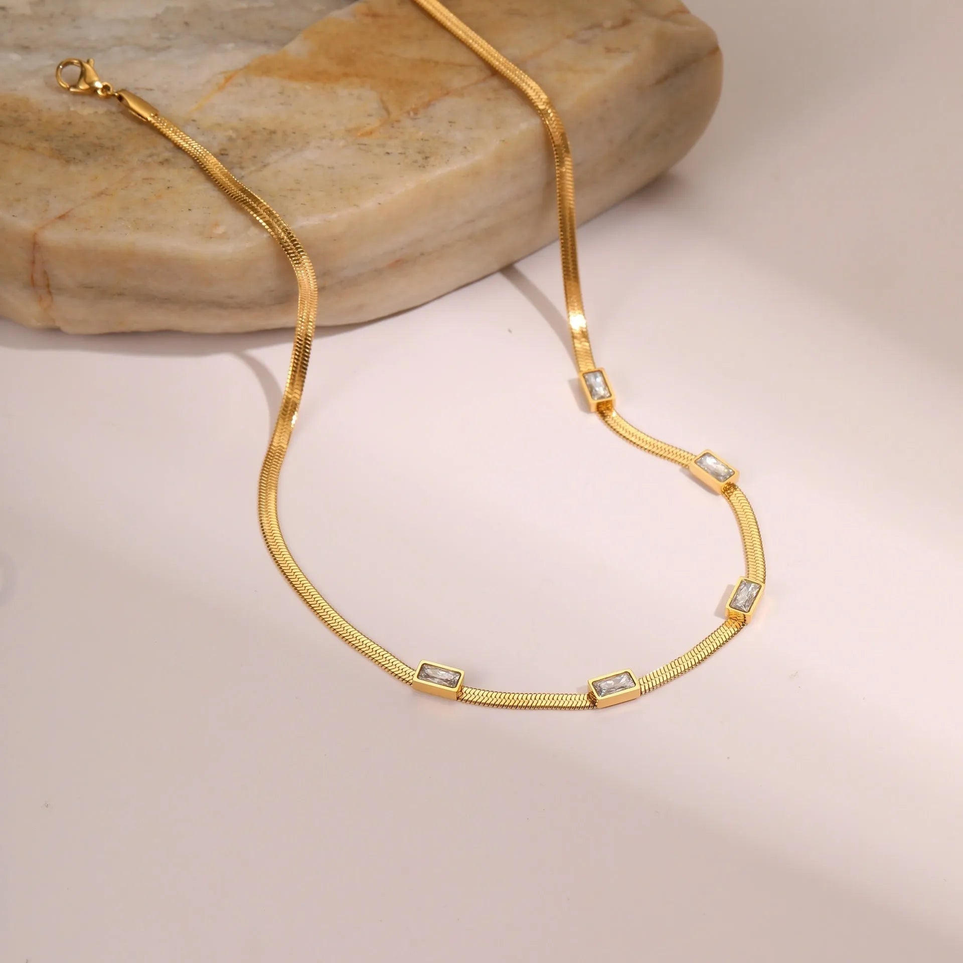 Geometric square pendant zircon necklace on a flat snake chain in gold or steel finish.