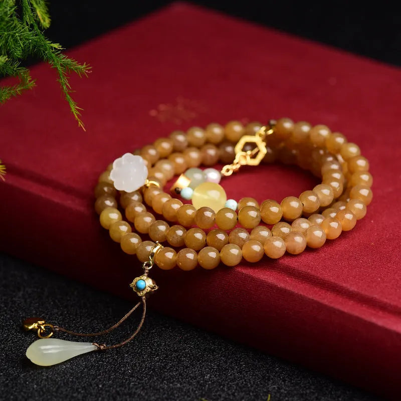 Green jade bracelet with round beads, pine elements, leaf designs, and sequin accents on wrist