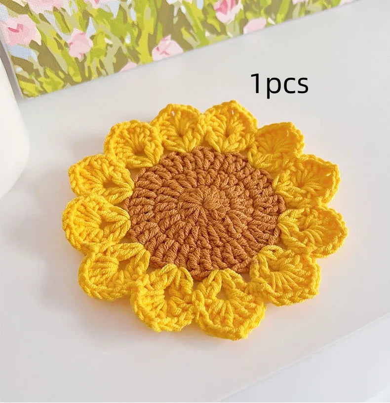Hand-woven wool coaster with floral pattern on a wooden table.