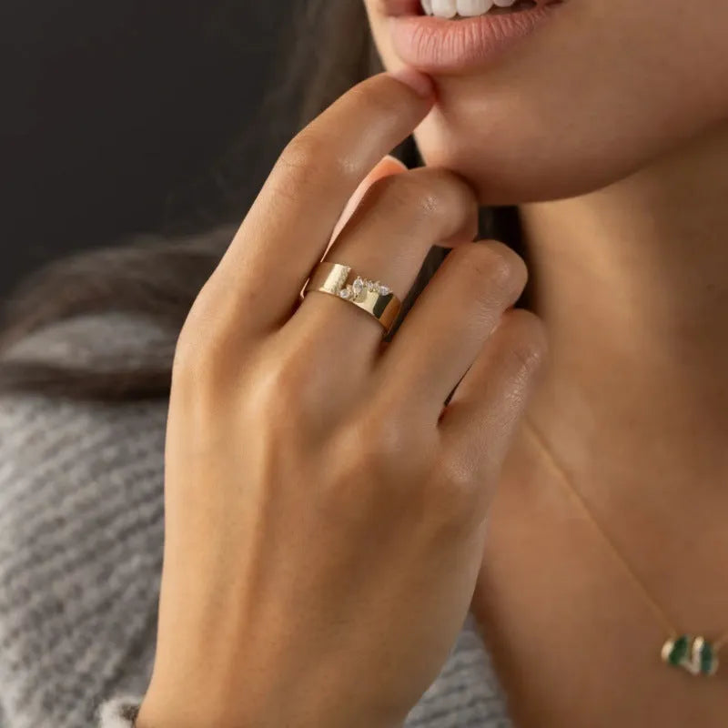 Gold electroplated copper ring with shining zircon stones on a finger.