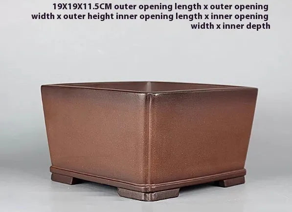 Brown handmade antique purple clay square flower pot on a windowsill.