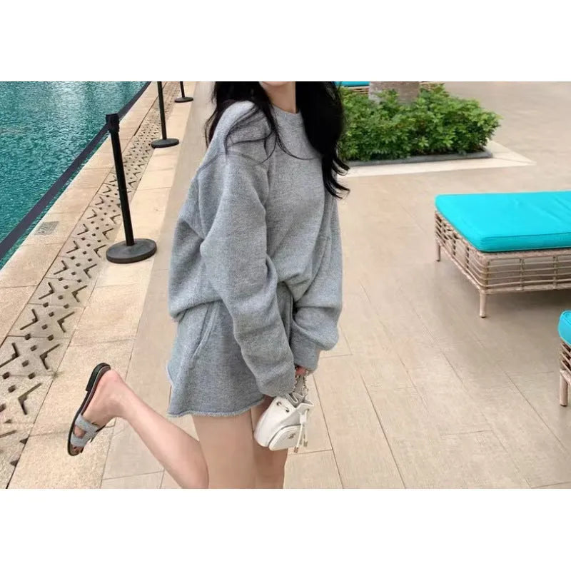 A woman's loose-fitting long sleeve knit sweater and matching wide-leg shorts set in a neutral colour.