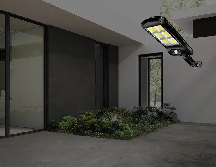 Black solar-powered outdoor motion sensor light mounted on a wall or fence post.