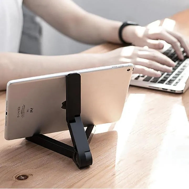 Black foldable tablet holder displaying adjustable angles with phone in landscape mode on non-slip surface