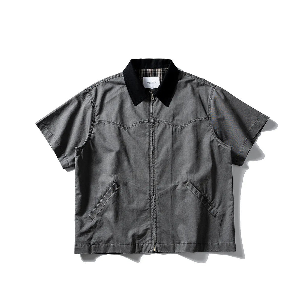 A khaki coloured, loose-fitting short sleeve cotton overalls shirt with a cardigan style on a hanger.