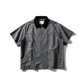 A khaki coloured, loose-fitting short sleeve cotton overalls shirt with a cardigan style on a hanger.