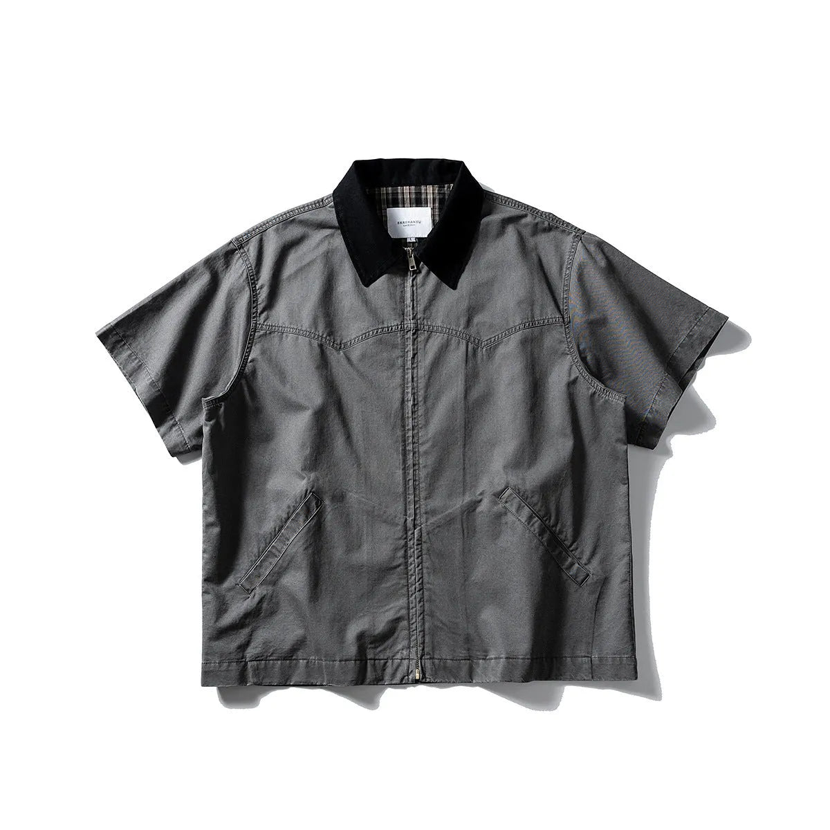 A khaki coloured, loose-fitting short sleeve cotton overalls shirt with a cardigan style on a hanger.