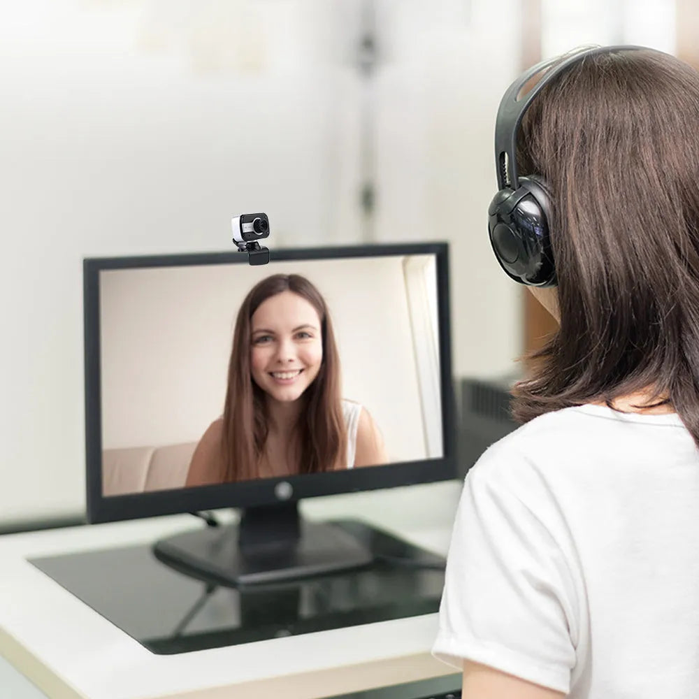 Blue mini USB webcam with a 360-degree rotating head on a desk next to a laptop.