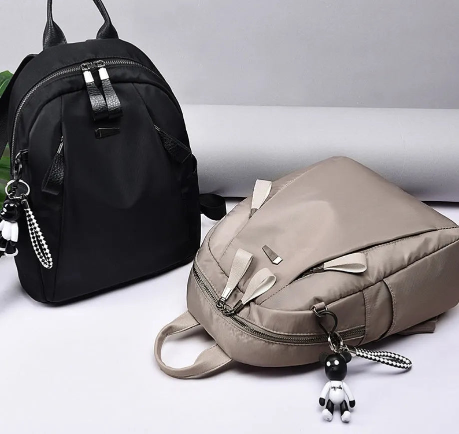 Medium square-shaped wine red Oxford cloth rucksack with double black straps and a soft handle.