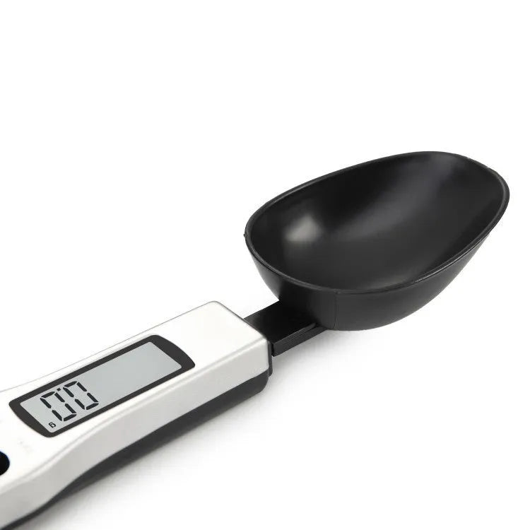Digital smart measuring spoon with LCD screen showing weight, placed next to mixing bowl.