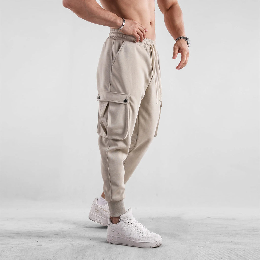 Men's loose grey cotton sports trousers with ankle ties and multiple pockets laid flat.