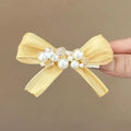 Yellow cloth bow barrette hair clip with rhinestone and pearl details on duckbill clip