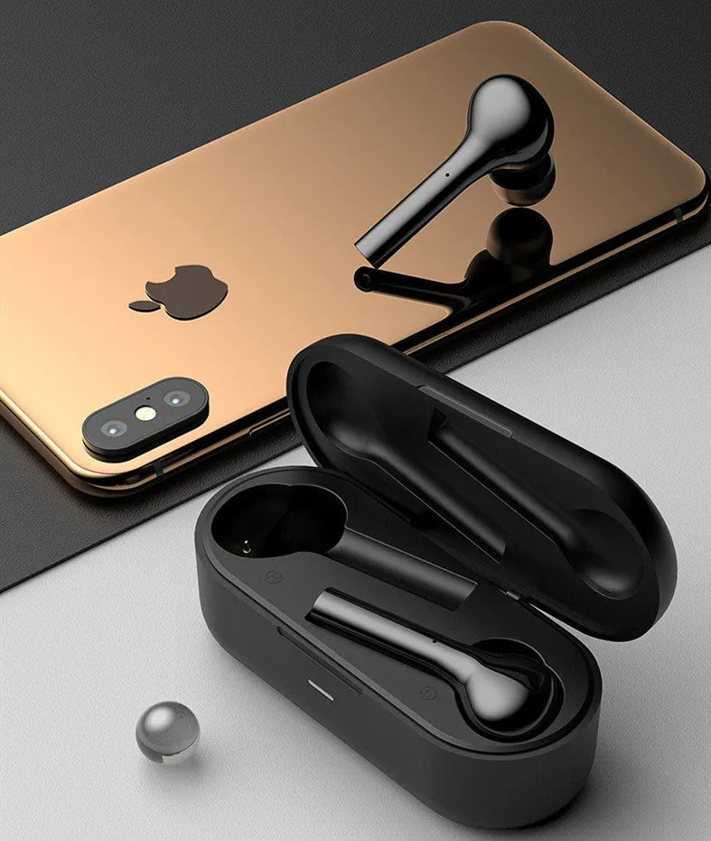 Black and white wireless in-ear Bluetooth headphones with a charging case on a table.