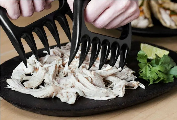 Two black bear claw meat shredding forks for barbecue preparation on kitchen surface