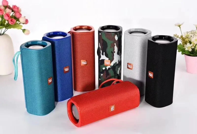 Cloth-covered portable Bluetooth speaker in multiple colours showing USB port and control buttons.