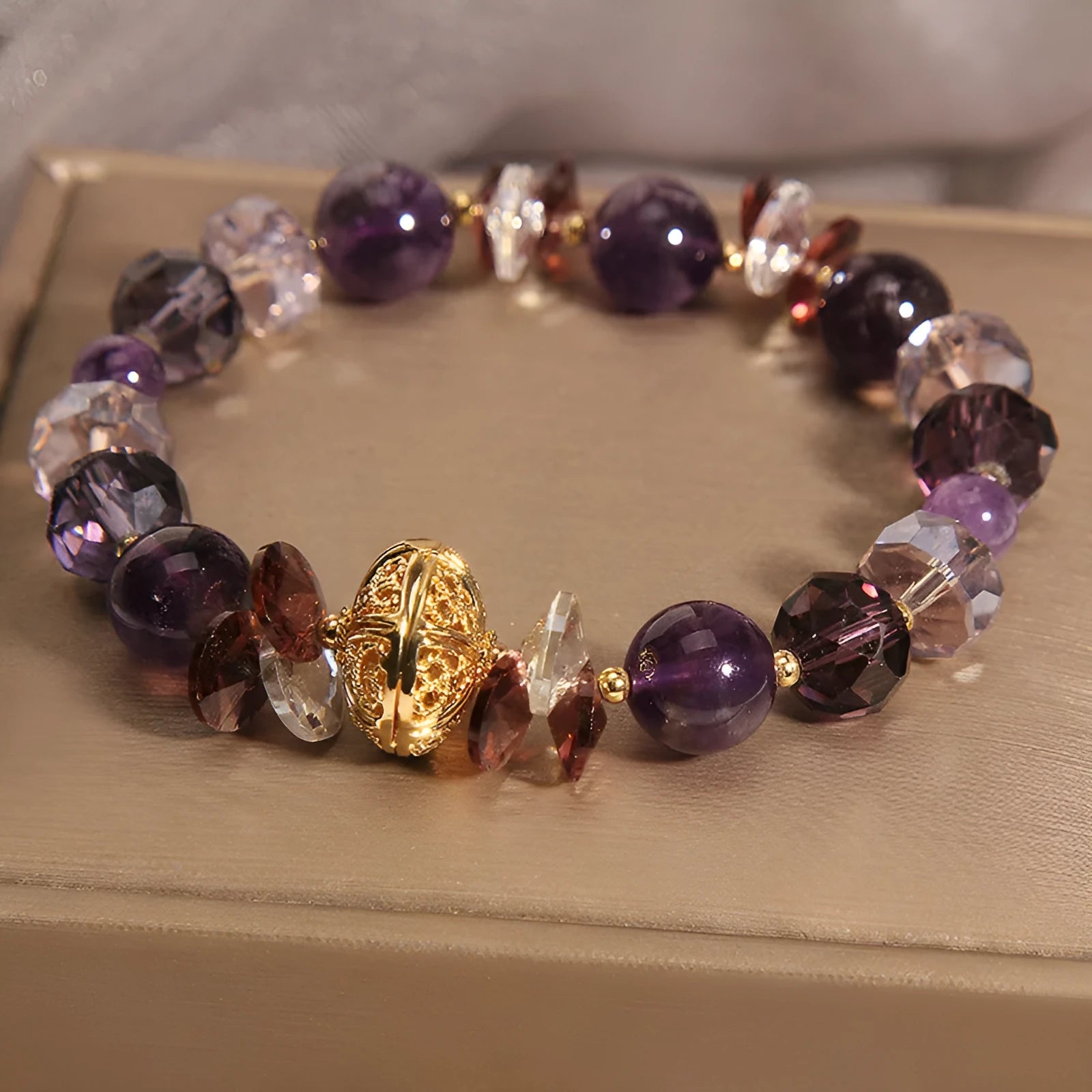Purple crystal bracelet with pumpkin beads and a wind chimes charm on wrist.