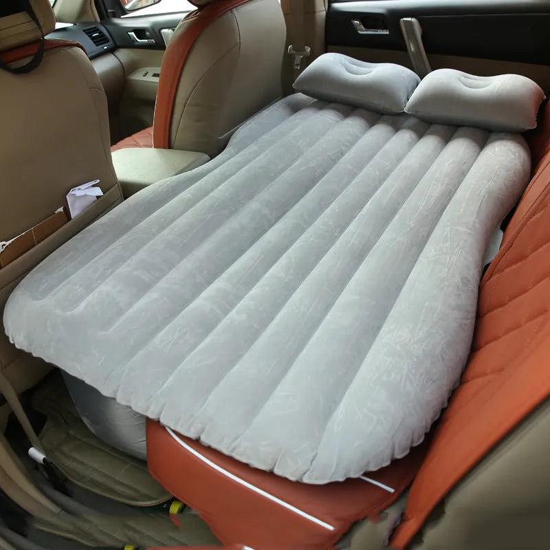 Inflatable car bed with flocked surface and two pillows, shown inside a five-seater vehicle.