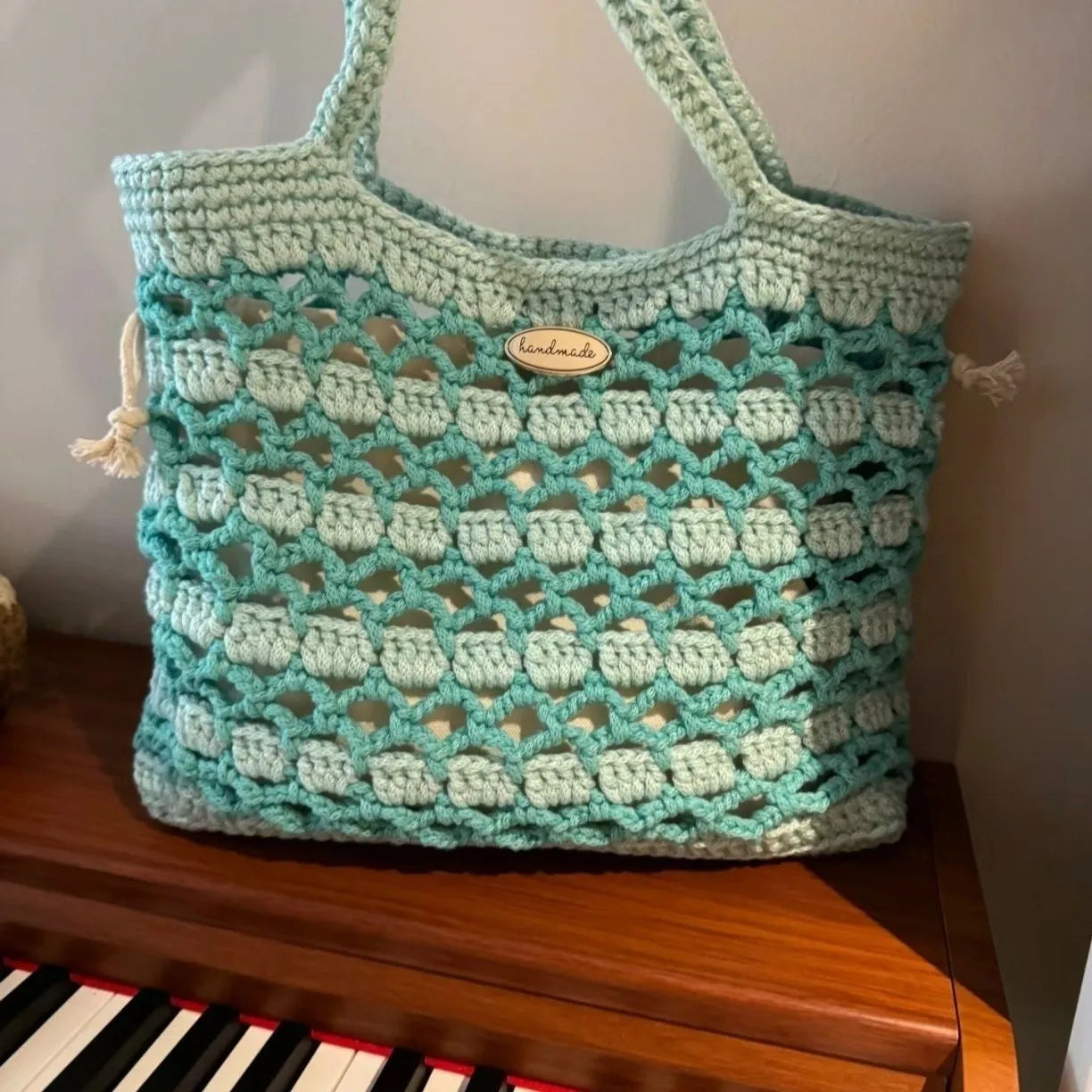Handmade woven shoulder bag with a floral pattern, made from soft wool yarn.