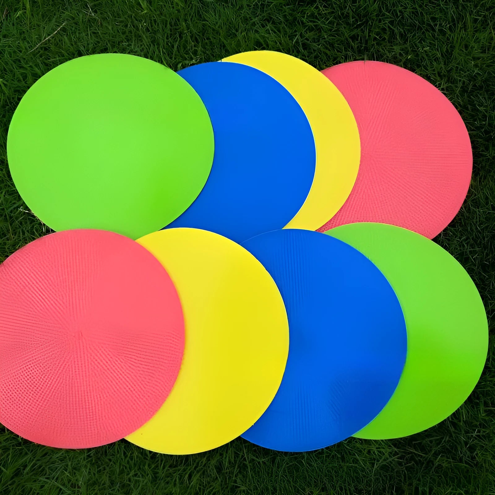 Soft TPE football training marker pad in assorted colours on grass, 23cm diameter.