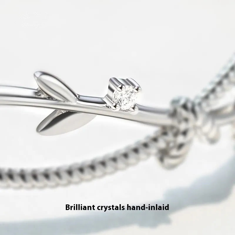 White gold sprout branch bracelet with cross twisted design on a wrist.