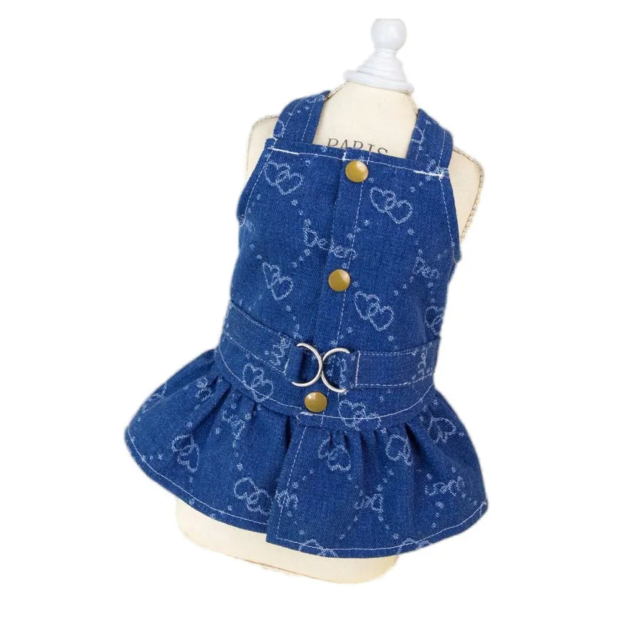 Small white dog wearing a light blue denim princess dress with a frilled skirt.