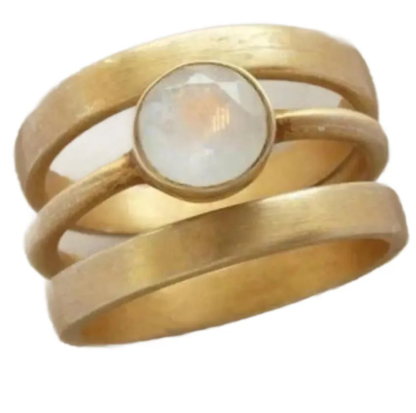 Gold-plated geometric ring with hollow band and inlaid white chalcedony stone on a grey background.