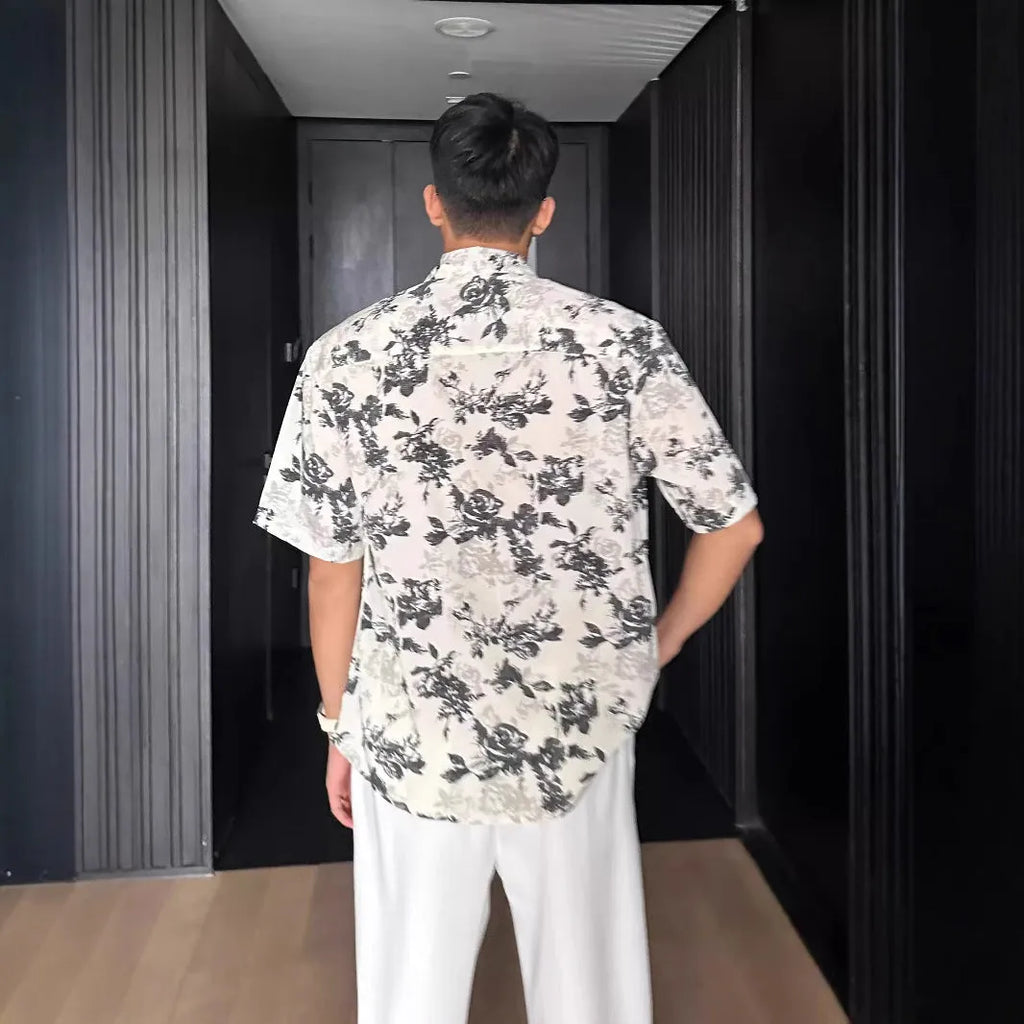 Man wearing a loose black short-sleeve shirt with a floral printed pattern.