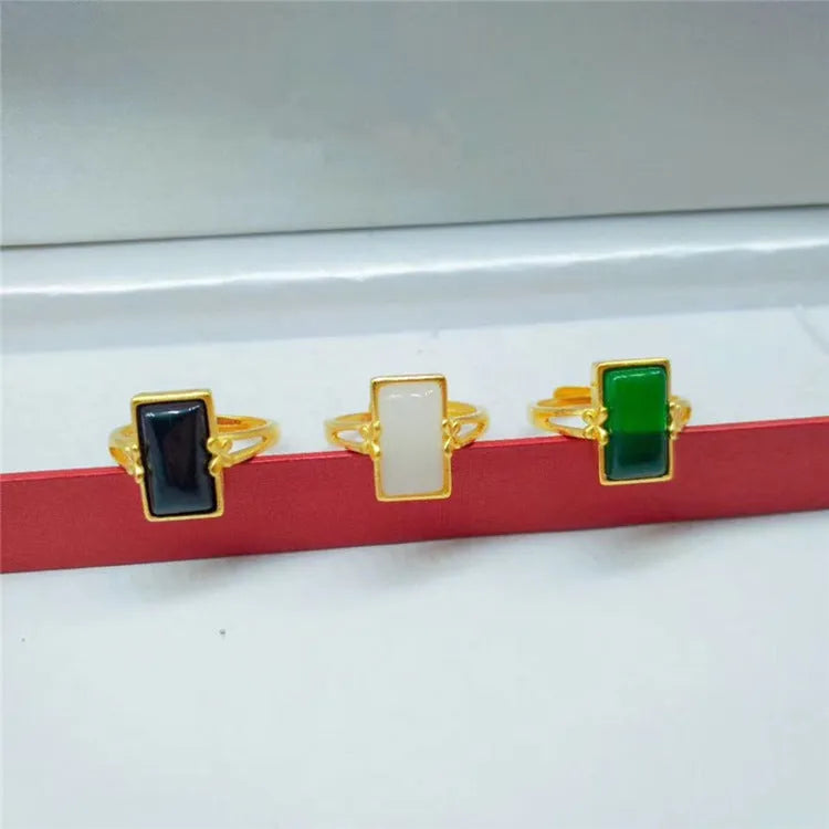 Adjustable gold plated brass ring with a national style design and a coloured inlaid gemstone.