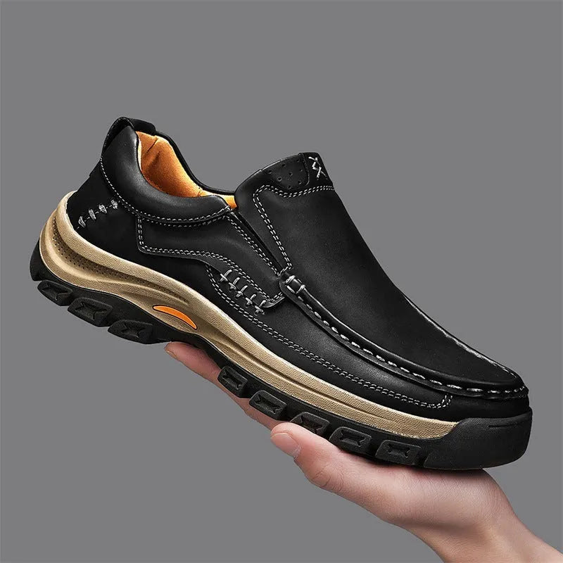 Men's black leather hiking shoes with thick rubber soles and round toe on a rocky outdoor path.