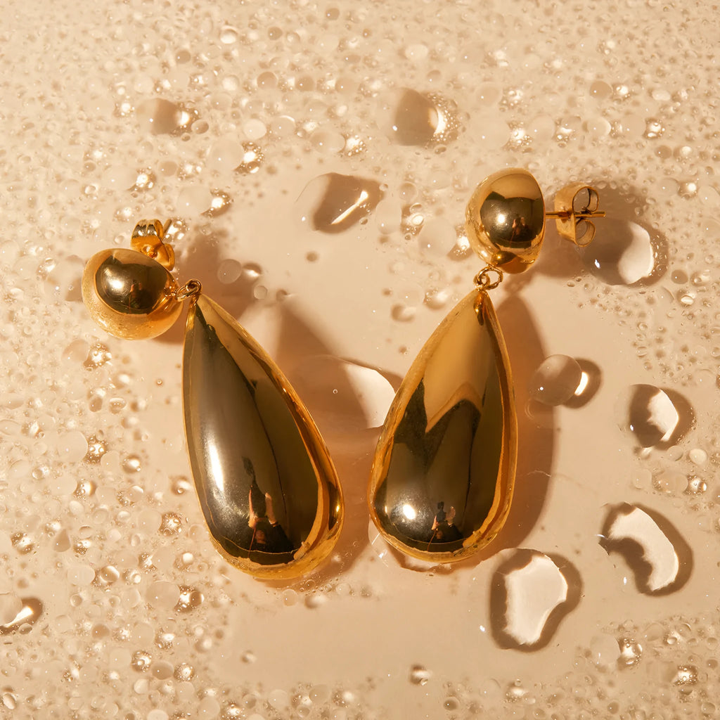 A pair of gold-coloured hemisphere-shaped earrings with a water drop pendant design, made from stainless steel.
