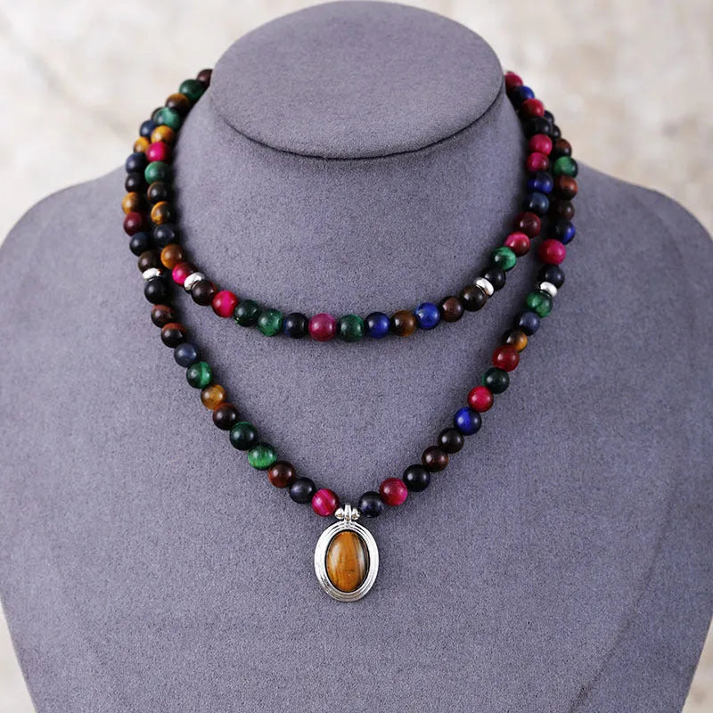 Close-up of a tiger-eye stone bead necklace with 108 gem-inlaid pendants showing heart, crown, and infinite symbols.