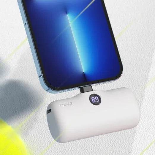 Compact white lipstick-shaped power bank showing screen display next to a smartphone.