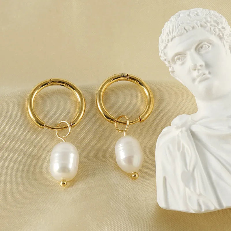 Gold geometric drop earrings with a freshwater pearl detail on a stainless steel setting.