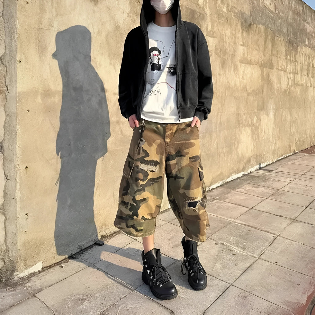 Man wearing loose straight-cut camouflage jeans with patch ripped detailing and a cropped ankle length.