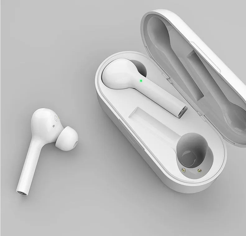 Black and white wireless in-ear Bluetooth headphones with a charging case on a table.