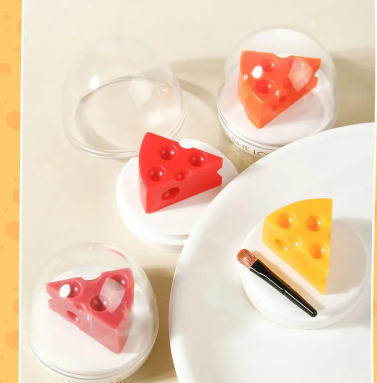 Pink cheese-shaped lip balm with Vitamin E and cream scent in open case with brush applicator