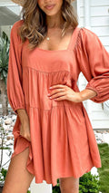 Orange red children's backless dress with square collar and puff sleeves on a mannequin.